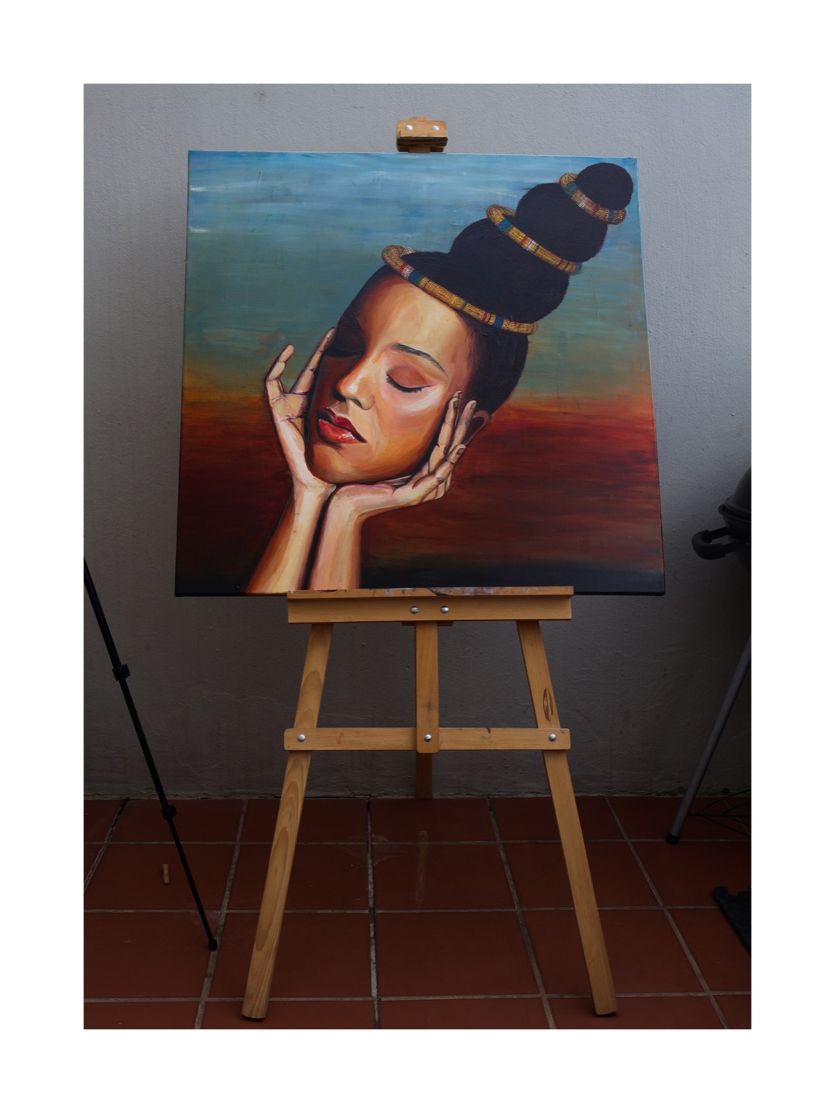 Obscurity — portrait of a woman with closed eyes, her face resting in her hands, a towering bun ringed with beadwork rising against a sky fading from blue into burnt orange; photographed on an easel